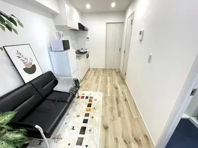 a living room with a black couch and a kitchen at Nishi-Ike Apartment Room 1 in Tokyo