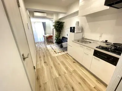 a kitchen with white cabinets and a wooden floor at Nishi-Ike Apartment Room 1 in Tokyo
