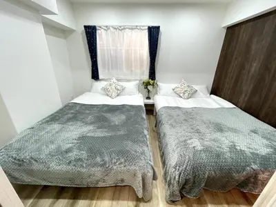 a bedroom with two beds and a window at Nishi-Ike Apartment Room 1 in Tokyo