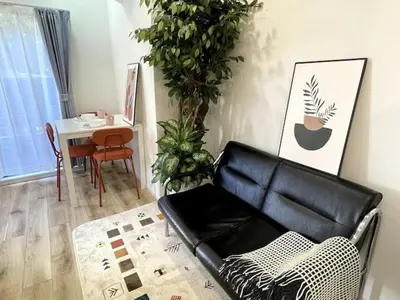 a living room with a black leather couch and a table at Nishi-Ike Apartment Room 1 in Tokyo