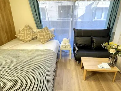 a bedroom with a bed and a couch and a table at Nishi-Ike Apartment Room 2 in Tokyo