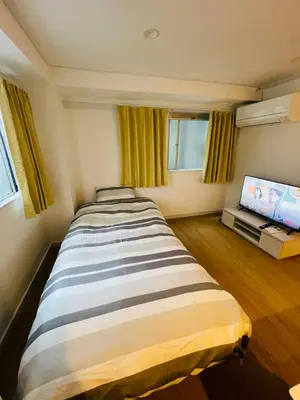 a large bed in a room with a flat screen tv at Home SHINJUKU west 101 in Tokyo