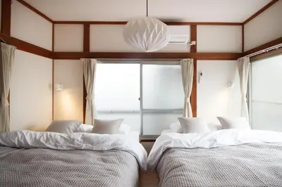 two beds in a room with a window at Saku House Jujo in Tokyo