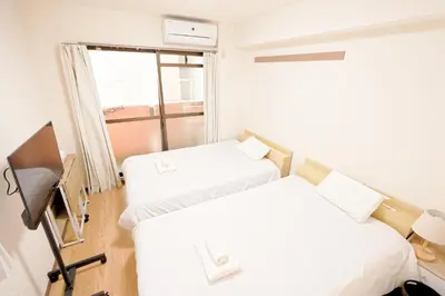 two beds in a room with a window at Shinjuku Waseda Earthtone Apartment in Tokyo