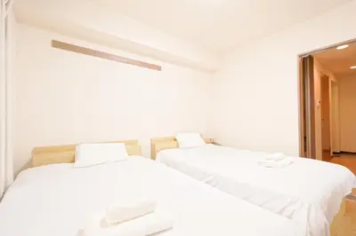 two beds in a room with white walls at Shinjuku Waseda Earthtone Apartment in Tokyo