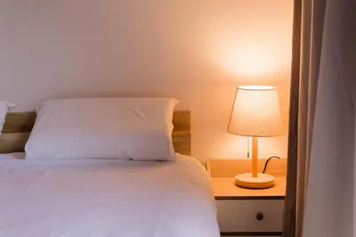 a bedroom with a bed and a lamp on a night stand at Shinjuku Waseda Earthtone Apartment in Tokyo
