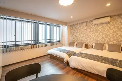 a hotel room with two beds and a window at \u6d45\u8349\u7985\u5fc3\u5c45201\u5ba4 \u6d45\u8349\u99c5\u5f92\u6b6915\u5206 2024\u5e744\u6708\u30cb\u30e5\u30fc\u30aa\u30fc\u30d7\u30f3 43\u5e73\u7c73\u4e38\u8cb8\u3057\u5207\u308a \u30c0\u30d6\u30eb\u30d9\u30c3\u30c82\u53f0\u3068\u7573\u6577\u304d\u5e03\u56e32\u7d44 \u5bb6\u5ead\u5f0f\u7528\u54c1\u8a2d\u5099\u5b8c\u5099 in Tokyo