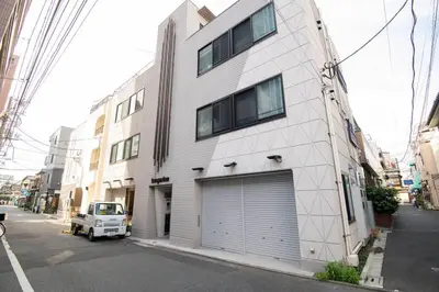 a white building with a garage door on a street at \u6d45\u8349\u7985\u5fc3\u5c45301\u5ba4 \u6d45\u8349\u99c5\u5f92\u6b6915\u5206 2024\u5e744\u6708\u30cb\u30e5\u30fc\u30aa\u30fc\u30d7\u30f3 43\u5e73\u7c73\u4e38\u8cb8\u3057\u5207\u308a \u30c0\u30d6\u30eb\u30d9\u30c3\u30c82\u53f0\u3068\u7573\u6577\u304d\u5e03\u56e32\u7d44 \u5bb6\u5ead\u5f0f\u7528\u54c1\u8a2d\u5099\u5b8c\u5099 in Tokyo