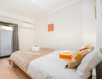 a bedroom with a bed with white sheets and a window at Aurora 2 in Tokyo