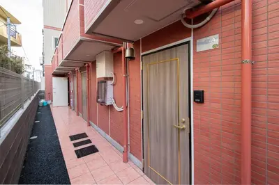 a hallway of a red brick building with a door at \u30aa\u30fc\u30b7\u30e3\u30f3\u30ba\u30b9\u30a4\u30fc\u30c8 \u6771\u4eac\u30c7\u30a3\u30ba\u30cb\u30fc\u30ea\u30be\u30fc\u30c8\u30b3\u30fc\u30b8\u30fc\u30d0\u30eb\u30b3\u30cb\u30fc302 in Tokyo
