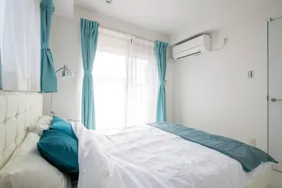 a bedroom with a bed with blue curtains and a window at \u30aa\u30fc\u30b7\u30e3\u30f3\u30ba\u30b9\u30a4\u30fc\u30c8 \u6771\u4eac\u30c7\u30a3\u30ba\u30cb\u30fc\u30ea\u30be\u30fc\u30c8\u30de\u30ea\u30f3\u30d0\u30eb\u30b3\u30cb\u30fc303\u5ba4 in Tokyo