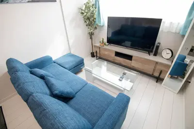 a living room with a blue couch and a tv at \u30aa\u30fc\u30b7\u30e3\u30f3\u30ba\u30b9\u30a4\u30fc\u30c8 \u6771\u4eac\u30c7\u30a3\u30ba\u30cb\u30fc\u30ea\u30be\u30fc\u30c8\u30de\u30ea\u30f3\u30d0\u30eb\u30b3\u30cb\u30fc303\u5ba4 in Tokyo