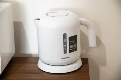 a white electric kettle sitting on a wooden table at \u30aa\u30fc\u30b7\u30e3\u30f3\u30ba\u30b9\u30a4\u30fc\u30c8 \u6771\u4eac\u30c7\u30a3\u30ba\u30cb\u30fc\u30ea\u30be\u30fc\u30c8\u30de\u30ea\u30f3\u30d0\u30eb\u30b3\u30cb\u30fc303\u5ba4 in Tokyo