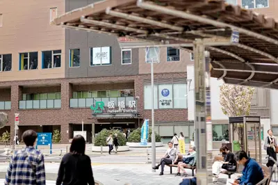a group of people sitting on benches in front of a building at Tokyo Kitaku hotel in Tokyo