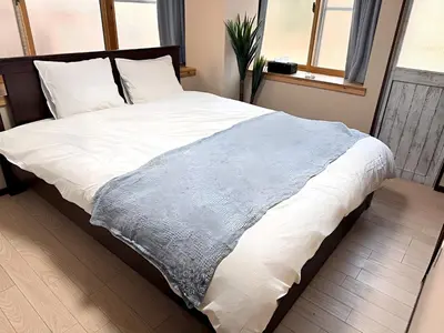 a large bed with white sheets and a blue blanket at Okubo Sta10min walk/ Shinjyuku Sta 2min/85 ㎡/3LDK in Tokyo