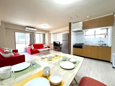 a living room with a red couch and a table at Okubo Sta10min walk/ Shinjyuku Sta 2min/85 ㎡/3LDK in Tokyo