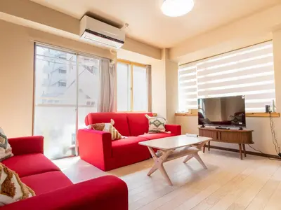 a living room with a red couch and a tv at Okubo Sta10min walk/ Shinjyuku Sta 2min/85 ㎡/3LDK in Tokyo