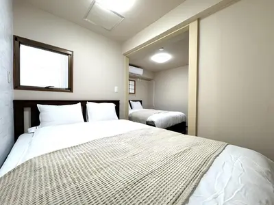a bedroom with two beds and a window at Okubo Sta10min walk/ Shinjyuku Sta 2min/85 ㎡/3LDK in Tokyo