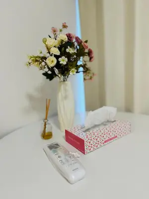 a remote control next to a box and a vase of flowers at 2 bedrooms entire house in Tokyo