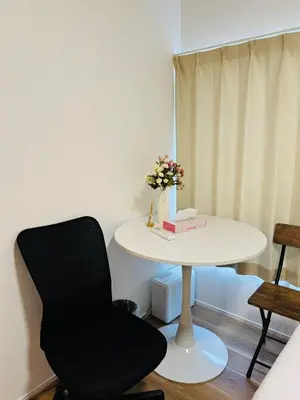 a white table with a black chair and a table with flowers at 2 bedrooms entire house in Tokyo