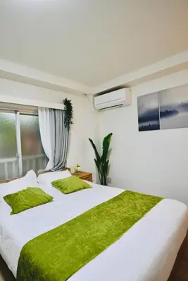 a bedroom with two beds with green pillows and a window at miyabi 3 - \u96c5 3 in Tokyo