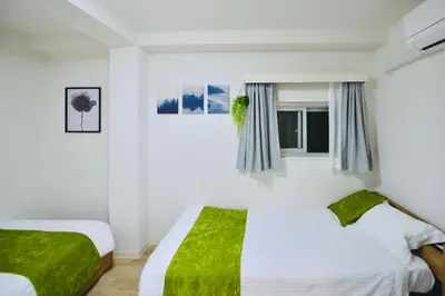 two beds in a white room with green sheets at miyabi 3 - \u96c5 3 in Tokyo