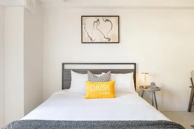 a bedroom with a bed with a yellow pillow on it at Dash Living Ueno Park in Tokyo
