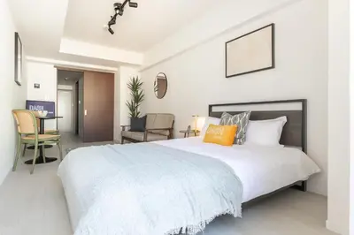 a bedroom with a large white bed with an orange pillow at Dash Living Ueno Park in Tokyo