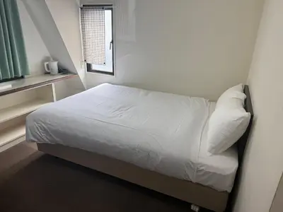 a bedroom with a bed with white sheets and a window at \u30a2\u30fc\u30d0\u30f3\u30db\u30c6\u30eb\u68ee\u4e0b in Tokyo