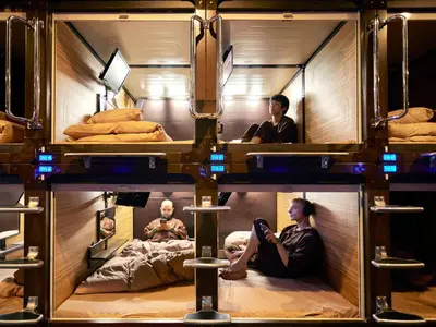 a group of people sitting in bunk beds at Anshin oyado Tokyo Man Ginza Shimbashi Station in Tokyo
