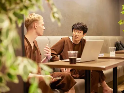 two men sitting at a table with a laptop at Anshin oyado Tokyo Man Ginza Shimbashi Station in Tokyo