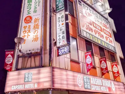 a building with many signs on the side of it at Anshin oyado Tokyo Man Ginza Shimbashi Station in Tokyo
