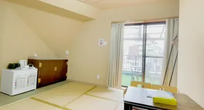 a living room with a table and a large window at Tokyo Holiday Hotel in Tokyo