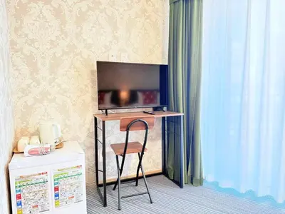 a room with a desk with a television and a chair at Tokyo Holiday Hotel in Tokyo