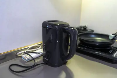 a black cup sitting on a counter with a pan at 7House in Tokyo