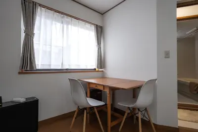 a room with a wooden table and chairs and a window at 7House in Tokyo