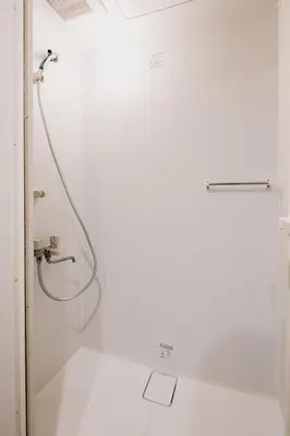 a shower with a hose in a white bathroom at Eminaz Minami Otsuka 2F in Tokyo