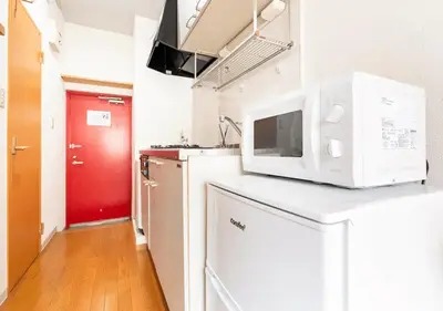 a kitchen with a microwave and a red door at 101 Shinjuku Modern Apartment Triple Station Access Free Wi-Fi in Tokyo
