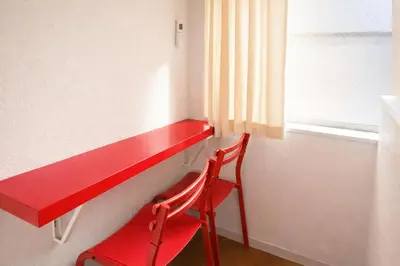 a red desk with a red chair next to a window at 101 Shinjuku Modern Apartment Triple Station Access Free Wi-Fi in Tokyo
