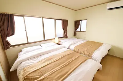 two beds in a room with two windows at \u6885\u5c4b\u6577\u8cb8\u5bb6 in Tokyo