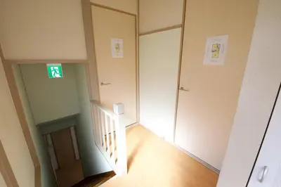 an empty hallway with a stairway with a green exit sign at \u6885\u5c4b\u6577\u8cb8\u5bb6 in Tokyo