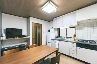 a kitchen with a wooden table and a kitchen with white cabinets at Ukiyoan Kachofugetsu in Tokyo
