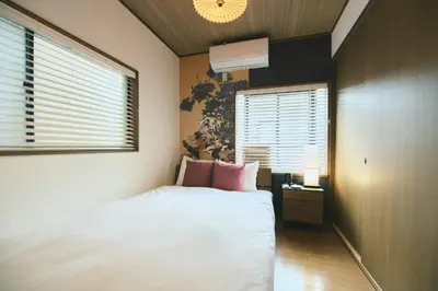 a bedroom with a bed with pink pillows and a window at Ukiyoan Kachofugetsu in Tokyo