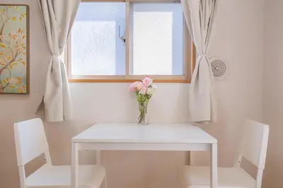 a vase of flowers on a white table with two chairs at walk to JR Shibuya sta.-SoE4 in Tokyo