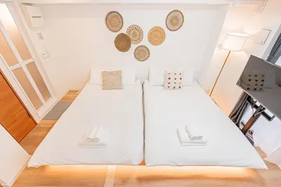 two beds in a room with white walls at Six7 Asakusa Ryogoku in Tokyo