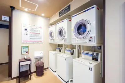 a laundry room with four washers and dryers at Anshin oyado Tokyo Man Shinjuku in Tokyo