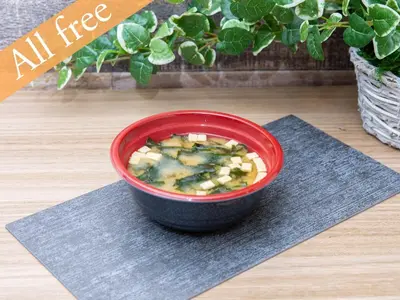 a red bowl of soup on a table with a plant at Anshin oyado Tokyo Man Shinjuku in Tokyo