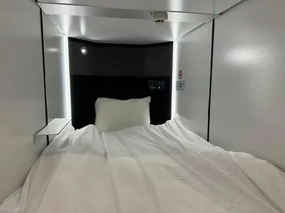 a white bed in a room with a mirror at Capsule Hotel Suzumoriya in Tokyo