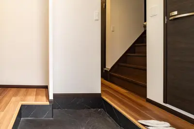 a hallway with a black door and wooden floors at 90, Yotsugi-A, private house rental, \u30ef\u30f3\u30d3\u30ec\u30c3\u30b8\u56db\u3064\u6728 in Tokyo