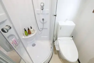 a white bathroom with a shower and a toilet at \u30ea\u30de\u30fc\u30eb\u30d3\u30eb2 401 in Tokyo